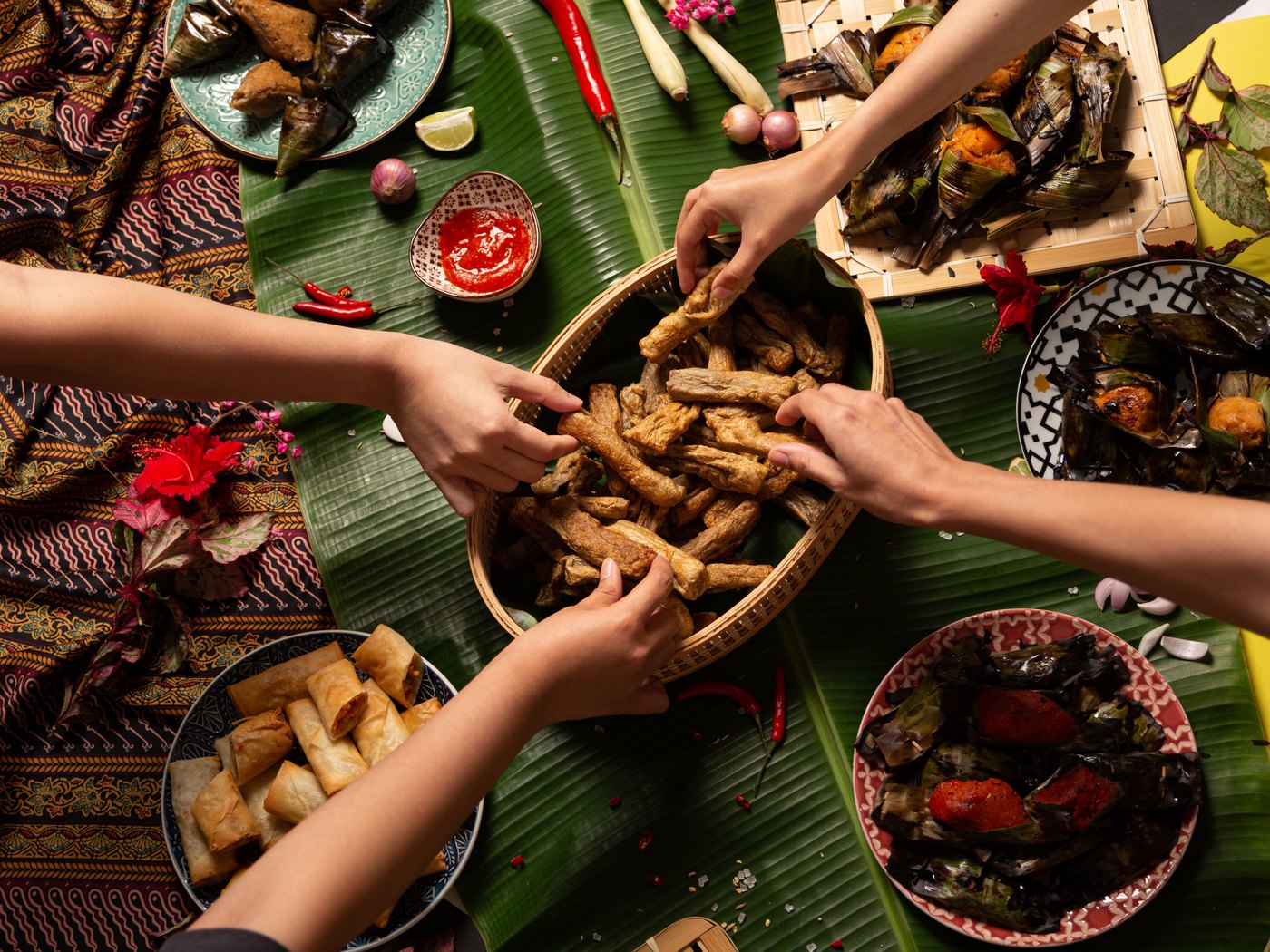 Hands reaching into a shared basket of keropok lekor